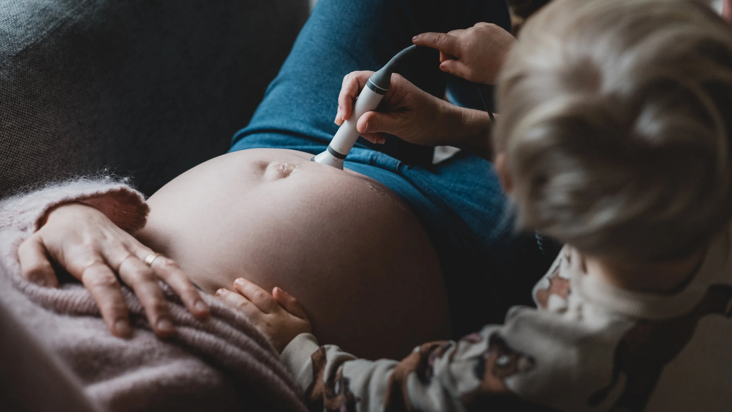 Rachel using a Doppler to listen to a baby's heartbeat during a home visit