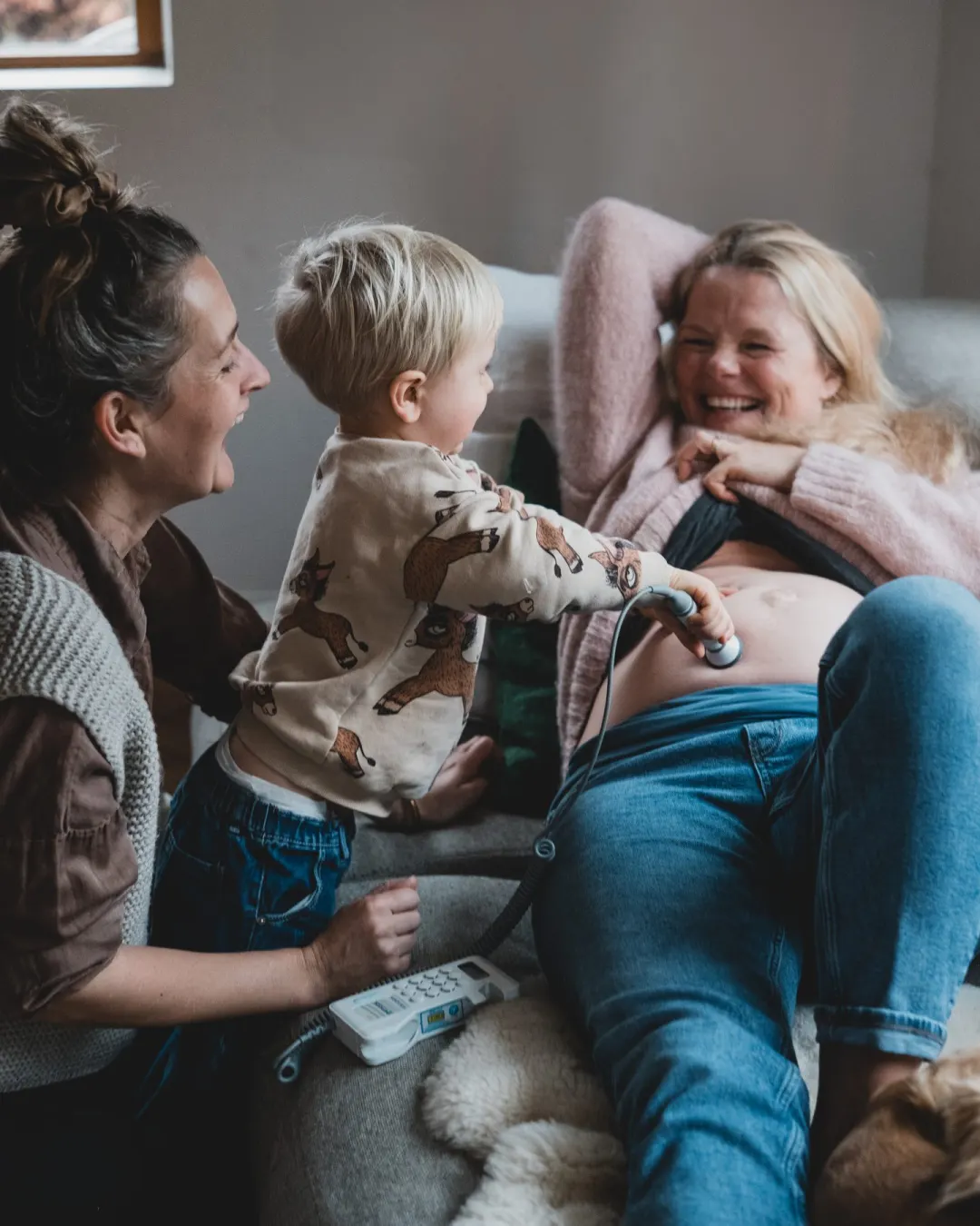 Rachel laughing with a mother and her toddler during a home visit